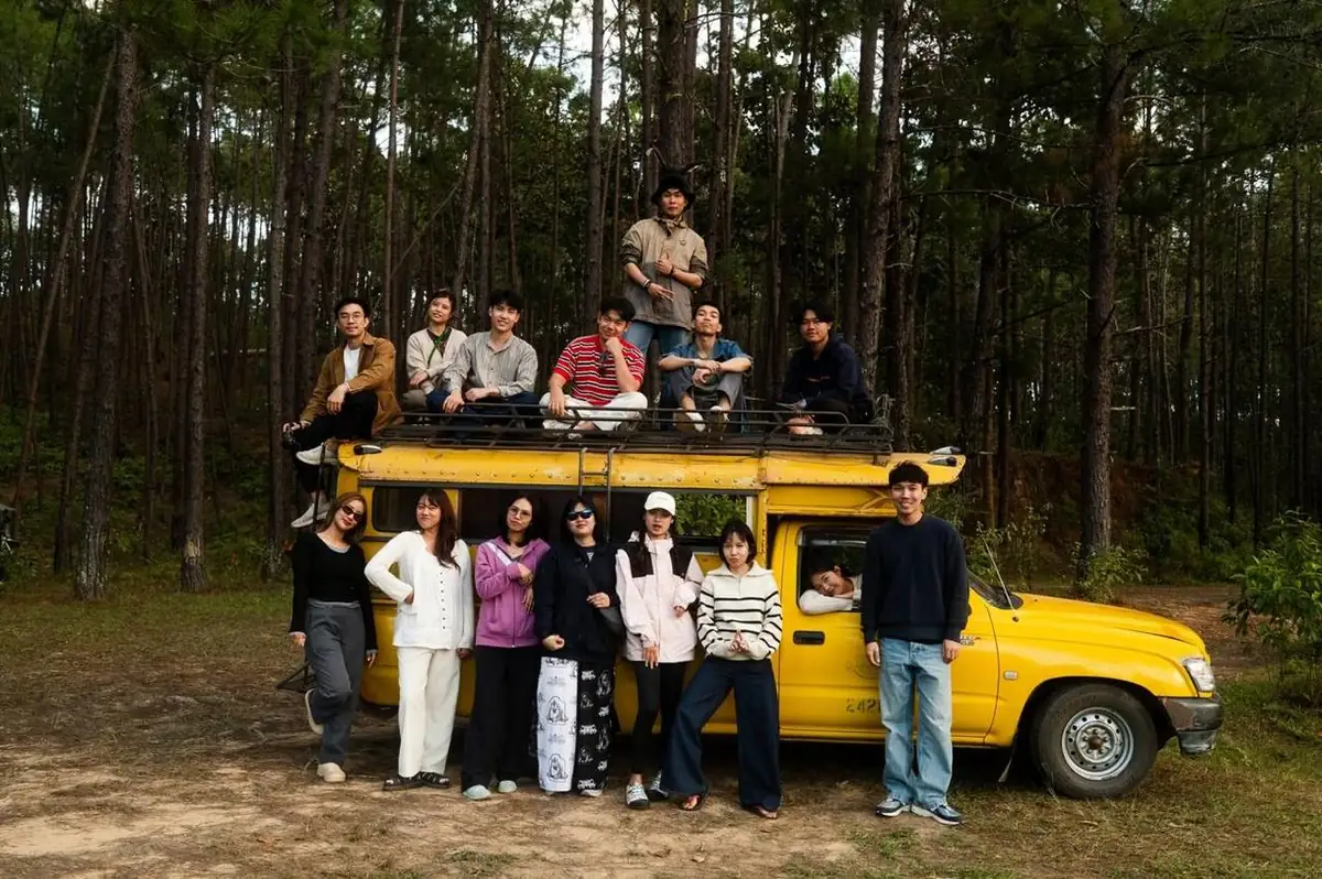 Kida with a big group of friends by his yellow truck in the pine forest